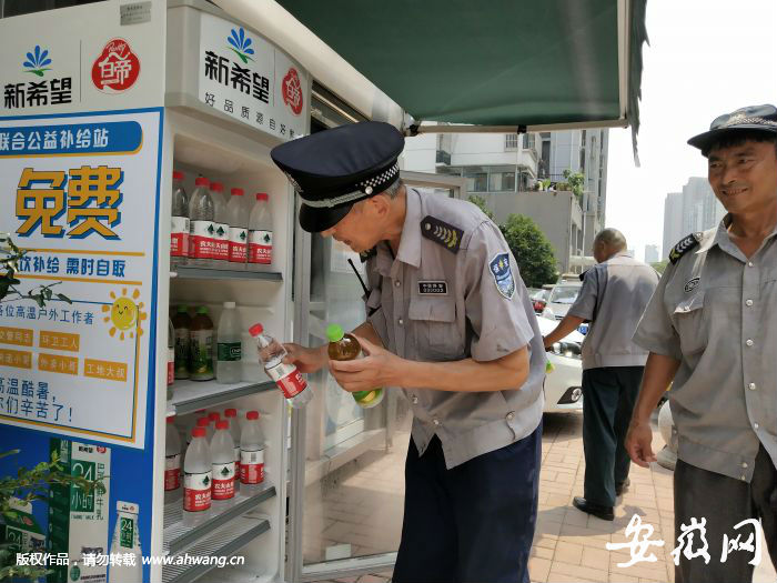 幾名保安在合肥市南七街道丁香社區的愛心冰箱里取水。