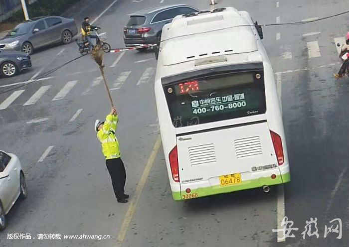 交警撑起电缆，公交车才得以通过。