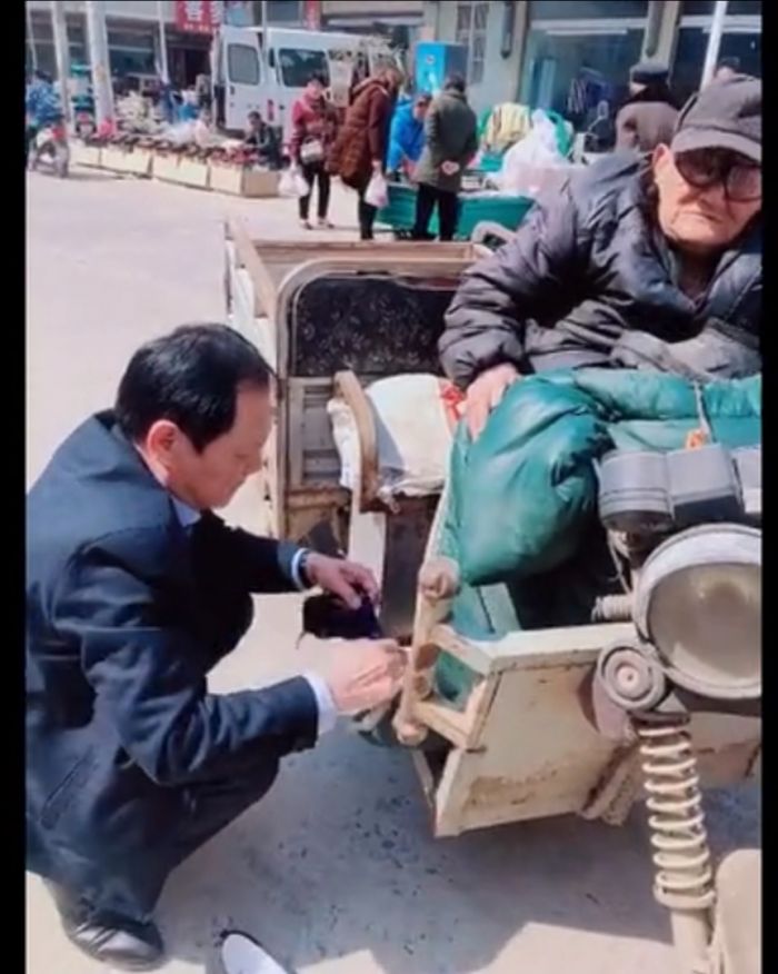 卢书林在给老人穿鞋袜。（视频截图）