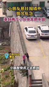 
小朋友悬挂围墙外情况危急 幸好两个小伙伴牢抓不放