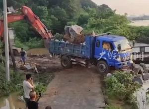 湖南汨罗一河段有堤坝决堤，当地用装满石头的卡车堵决堤口